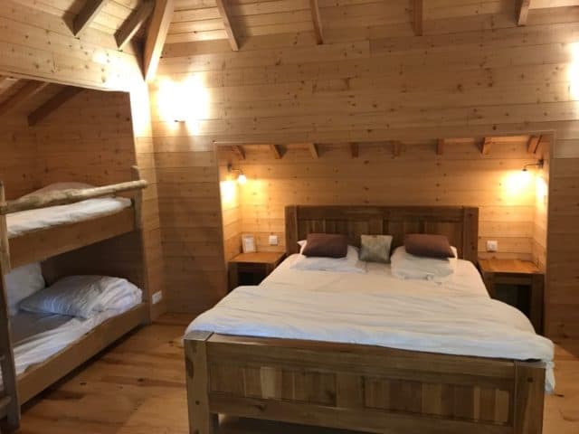 La chambre de la cabane Ecôtelia avec un grand lit et un lit superposé